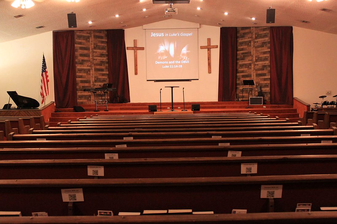 Rows of wooden pews facing the platform and two crosses in the old worship center