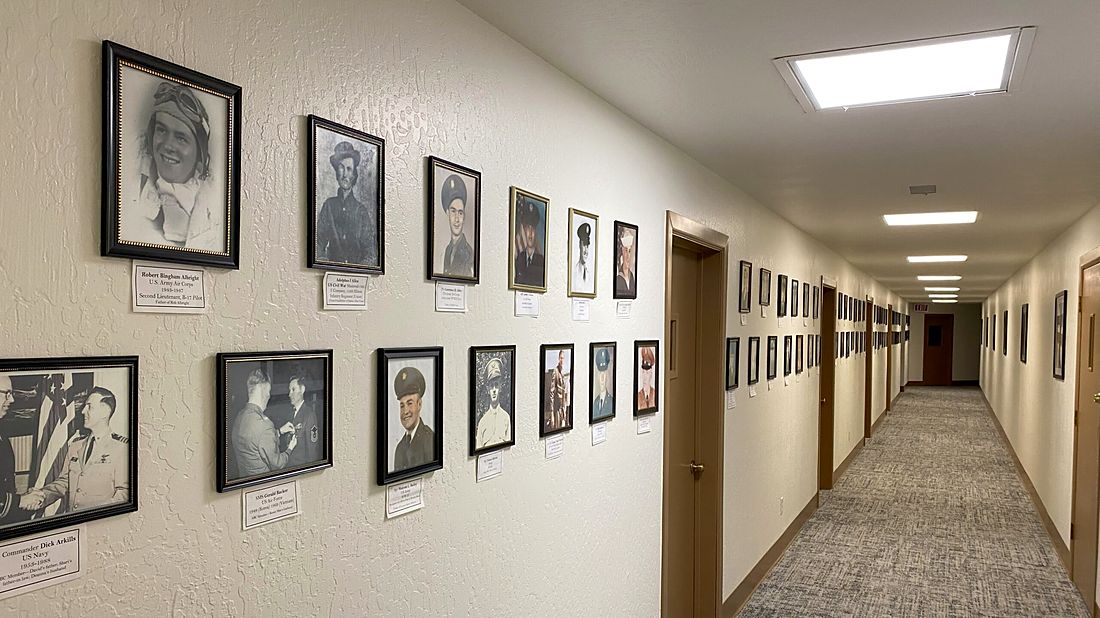 A hallway of framed portraits honoring members’ family who served in the military
